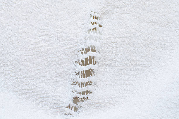Vertical rip and hole in old worn white terry cloth towel