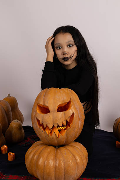 istock Little girl sitting on table with pumpkin, smiling brightly 2240829341