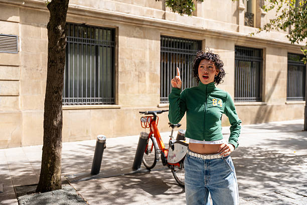 istock Young woman pointing upwards while standing next to a bike 2240834804