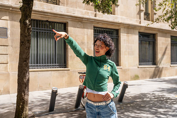 istock Young woman pointing and smiling in urban setting 2240834954