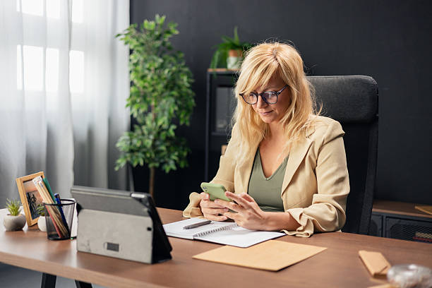 istock Businesswoman using smartphone at office desk, working remotely 2240835031