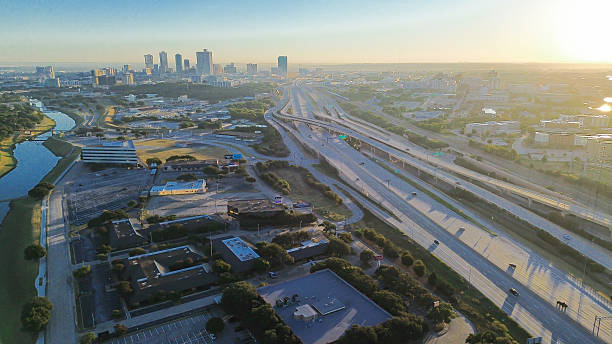istock Stacked interchange near Fort Worth divides downtown skyline from industrial logistics zone, elevated ramps, freight access, and golden hour light casting long shadows across both sectors, Texas 2240836330