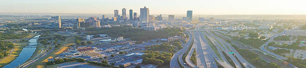istock Panorama aerial view stacked interchange near Fort Worth divides downtown skyline from industrial logistics zone, elevated ramps, freight access, golden hour light casting long shadow, Texas 2240836376
