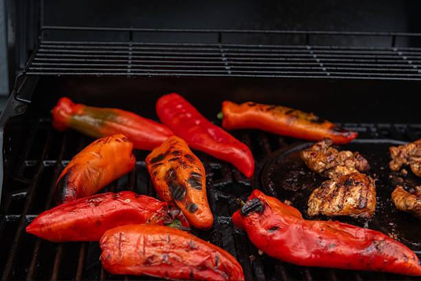 Juicy grilled chicken and red peppers sizzling on a barbecue, capturing the flavor and warmth of outdoor summer cooking.