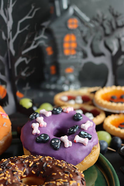 istock Image of spooky halloween iced ring doughnuts with candy / festive party cakes, creative dessert treats 2240841326