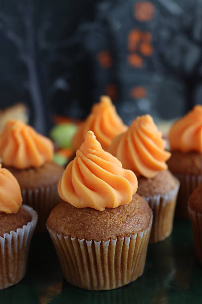 A piece of carrot cupcake with icing and a walnut decoration on a wooden table, surrounded by Christmas decorations.