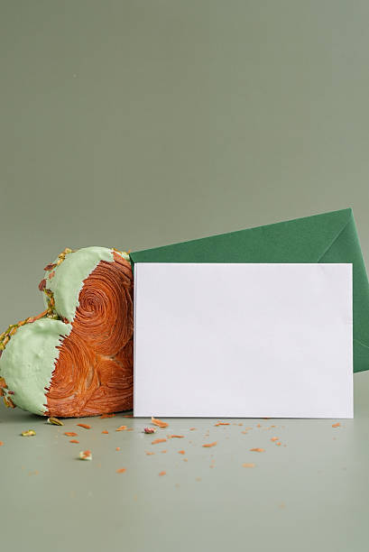 istock Empty template paper note with envelope greeting card mock up. Heart shaped pistachio croissant on green background with copy space. Puff pastry trendy sweet dessert bakery. Creamy dough experiment 2240844568