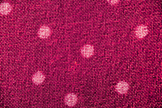 A close-up of a white fabric with an evenly spaced red polka dot pattern, showcasing textile design, texture, and pattern aesthetics.