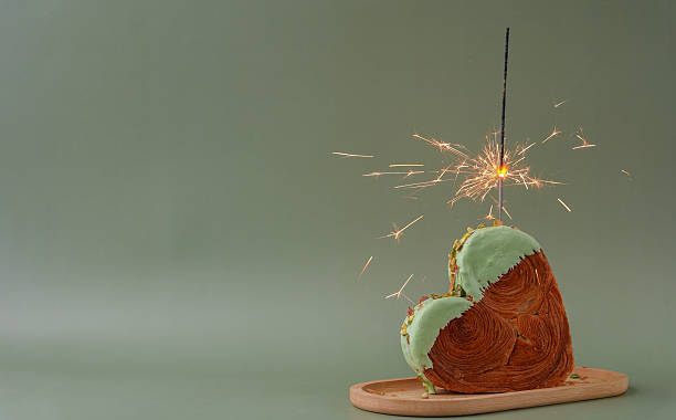 Shiny festive candle sparkler birthday celebration holiday Delightful and vibrant heartshaped pastry croissant treat, beautifully topped with colorful frosting nut galore. Mock up template copy space. Food experimentation viral dessert creative
