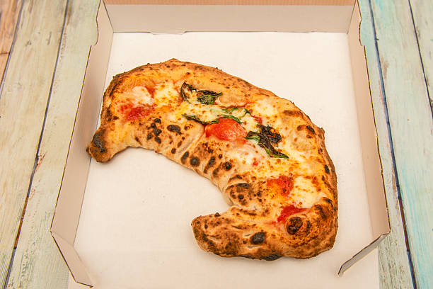 delicious looking calzone with melted cheese, cherry tomatoes and basil in a home delivery box