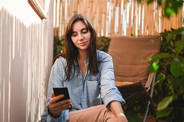istock Woman relaxing on balcony scrolling mobile phone 2240852832