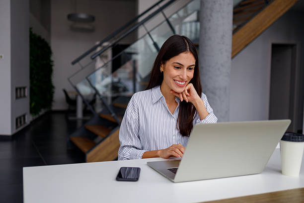 istock Smiling businesswoman using laptop, working from modern office, collaborating remotely with team 2240860210