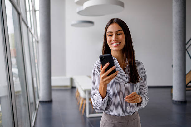 istock Businesswoman looking at smartphone in modern office building, using mobile technology for communication and professional tasks 2240861333