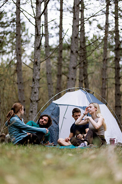 istock Group of friends enjoying a camping trip in a forest during spring while sitting outside their tent and sharing stories on a sunny day 2240865211