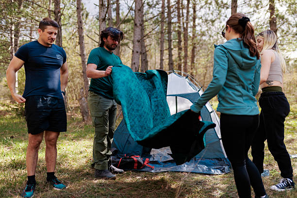 istock Friends setting up a camping tent in a serene forest during a sunny afternoon getaway 2240865226