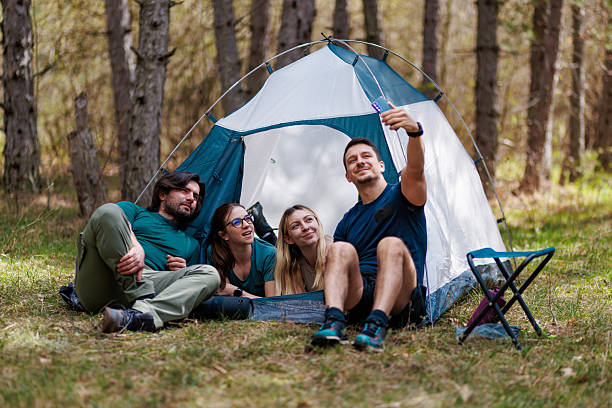 istock Friends enjoying camping together in a forest while taking a selfie inside their tent on a sunny day 2240865240