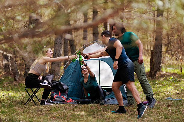 istock Camping trip with friends sharing drinks and laughter in a forest setting during a sunny afternoon 2240865263