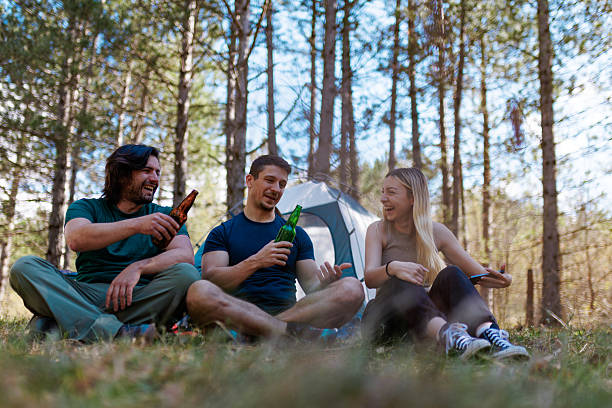 istock Friends enjoy a relaxing camping trip in the woods while sharing drinks and laughter on a sunny day surrounded by nature 2240865279