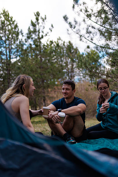 istock Friends enjoying a relaxed moment while camping in the woods on a sunny day with warm drinks and laughter 2240865285