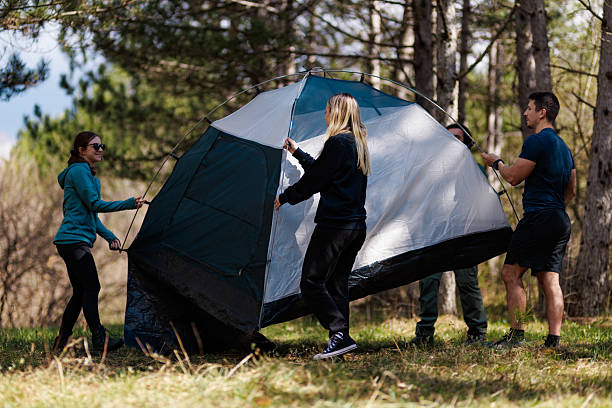 istock Friends setting up a tent during camping in a forested area on a sunny day for a weekend getaway 2240865300