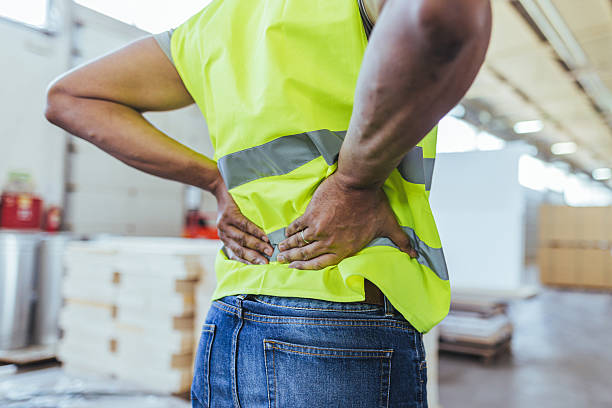 istock Worker in Safety Vest Experiencing Back Pain in Industrial Environment 2240865366