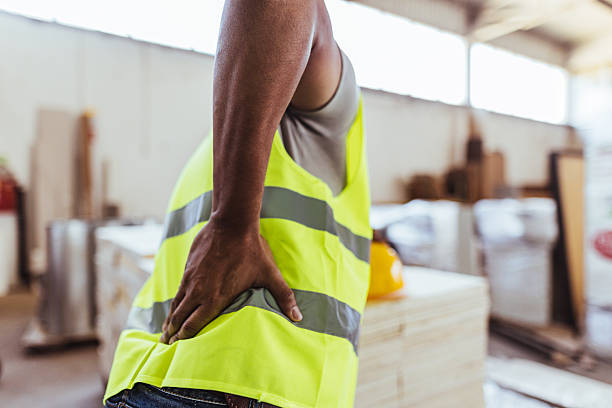 istock Worker Experiencing Back Pain in a Factory Workspace Wearing Yellow Vest 2240865396