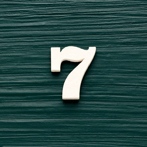 istock Number seven - White wooden number on a rustic dark green background 2240867850