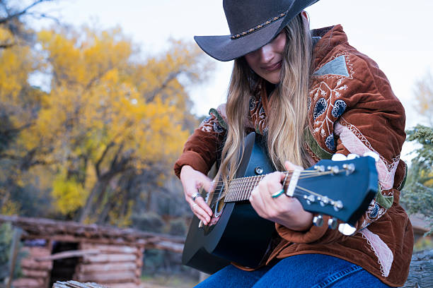 istock Cowgirl Playing Guitar Outdoors in Autumn 2240870918