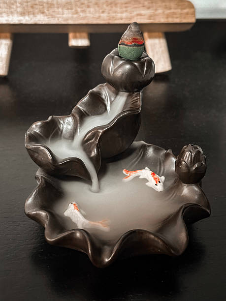 Artistic ceramic incense burner with koi fish detail and backflow smoke effect, creating a peaceful and zen-inspired ambiance on a dark surface