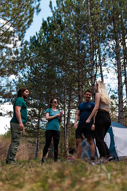 istock Friends enjoying a camping trip in a forest clearing while having fun and sharing laughter surrounded by tall trees and nature 2240872304