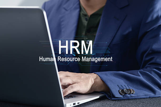 istock Stylish Businessman Working on Laptop with HRM Theme Displayed 2240876959