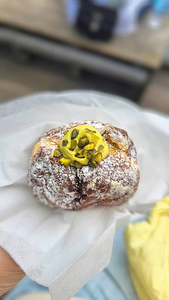 istock Enjoy Fresh Pistachio Cream-Filled Fried Doughnut in takeout Paper Bag While Walking Through Tokyo Streets – Popular Street Food Dessert, High-Calorie Sweet  Afternoon Tea 2240892757