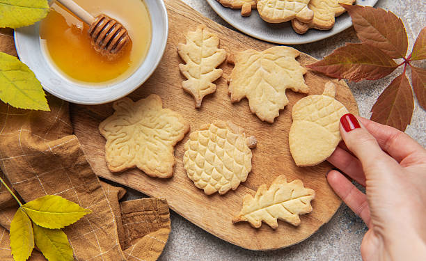 istock Hand holding fall themed shortbread cookies with honey 2240900845