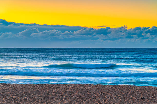 Sunrise seascape with low cloud bank and waves at Bilgola Beach on the Northern Beaches of Sydney, NSW, Australia.