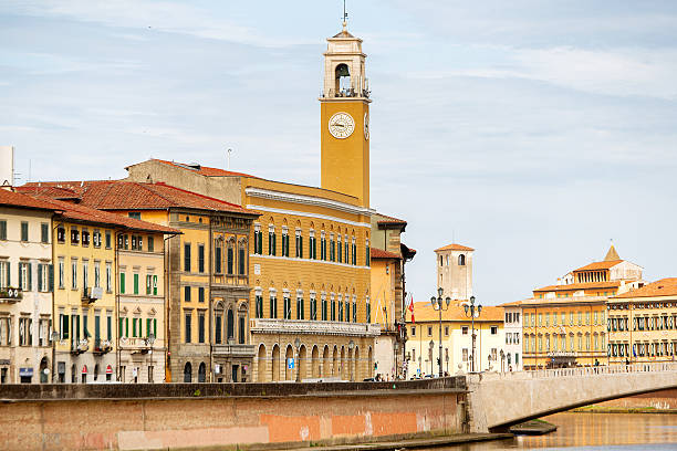 Atmospheric night scene of Pisa along the Arno River, featuring a row of historic buildings illuminated by warm streetlights. Golden reflections shimmer across the calm river surface, creating a dramatic contrast against the deep black sky. This long-exposure style cityscape captures the romantic ambiance of an Italian riverside at night and is ideal for themes of European travel, urban nightlife, architecture, reflections, and classic Italian city scenery.