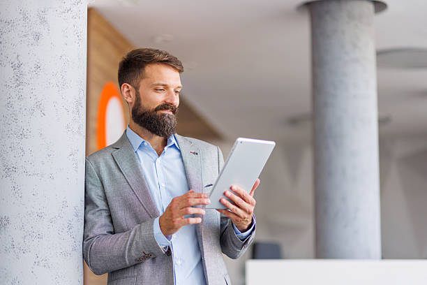 istock Bearded businessman holding digital tablet in modern office 2240905997