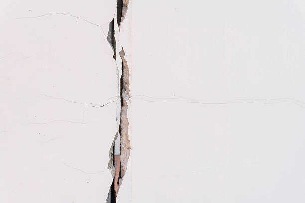Detailed crack line on white cement wall for construction defect or old building texture background.
