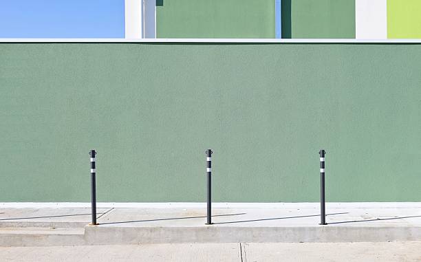 istock Black safety bollards on sidewalk with green plaster wall on behind. 2240907613