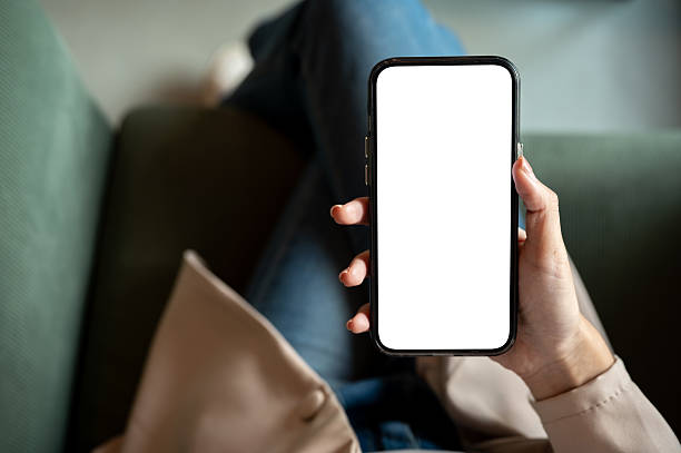 istock Close up woman's hand holding blank screen smartphone while sitting on green sofa in cafe or lounge. 2240908944