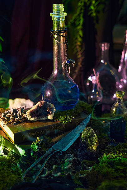 istock collection of colorful bottles, sparkling crystals, and an open book sit on soft moss inside a dimly lit room. Ethereal smoke swirls around, creating a magical atmosphere 2240910630