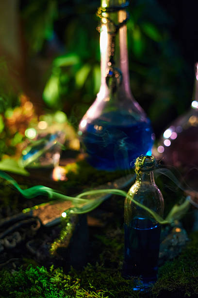 istock Bottles of blue potions rest on mossy ground in a forest. Soft light creates a magical atmosphere as nearby artifacts glimmer. scene is enchanting and evocative of fantasy tales 2240910638