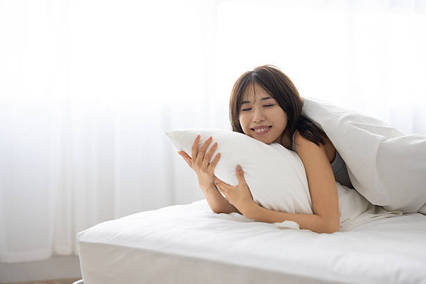 istock Young Woman Sleeping While Hugging Pillow in Cozy Bed 2240912450