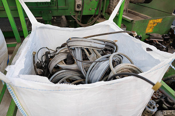 Large white industrial sack containing coiled rubber waste, used hoses stored for recycling in a processing plant