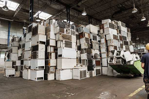 Worker controlling forklift to move large containers of mixed e-waste in a modern recycling plant