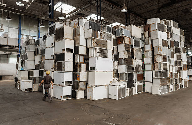 istock Industrial scene with worker passing by stacks of old fridges 2240914247