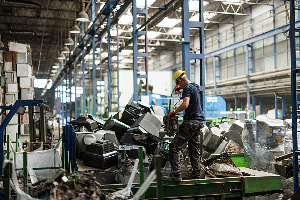 Modern recycling plant interior showing professional technician safely disassembling electronic devices