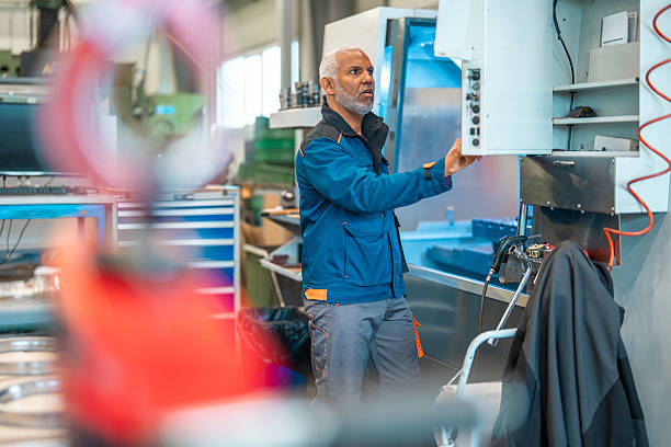 istock Mature Hispanic Male Technician Operating CNC Machine in Industrial Workshop 2240916630