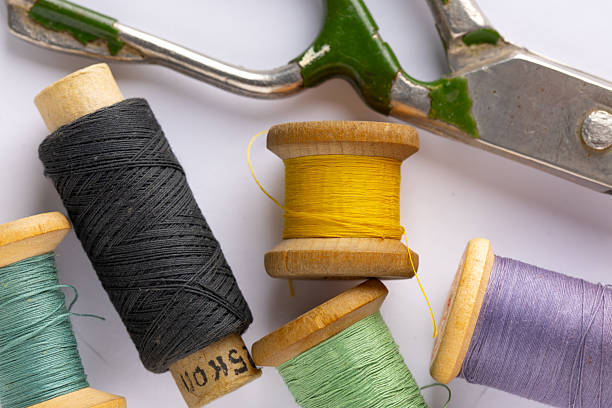 Tools in a sewing workshop - vintage spools of thread in different colors and antique metal tailor's scissors on a white background