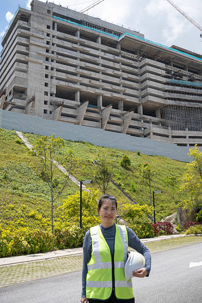 A large, modern multi-storey building in the midst of construction, featuring curved facades, tall vertical columns, and open concrete floors. The architectural design showcases sleek, rounded edges and a contemporary aesthetic. Scaffolding and building materials are visible throughout the lower levels, highlighting active construction work. The image captures the scale, complexity, and emerging form of a significant architectural project
