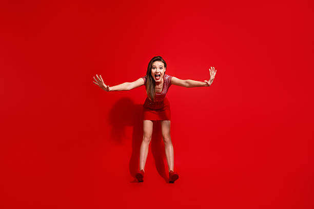 istock Excited young woman posing with dynamic gestures on a vibrant red background, expressing joy and charisma, copyspace 2240920003